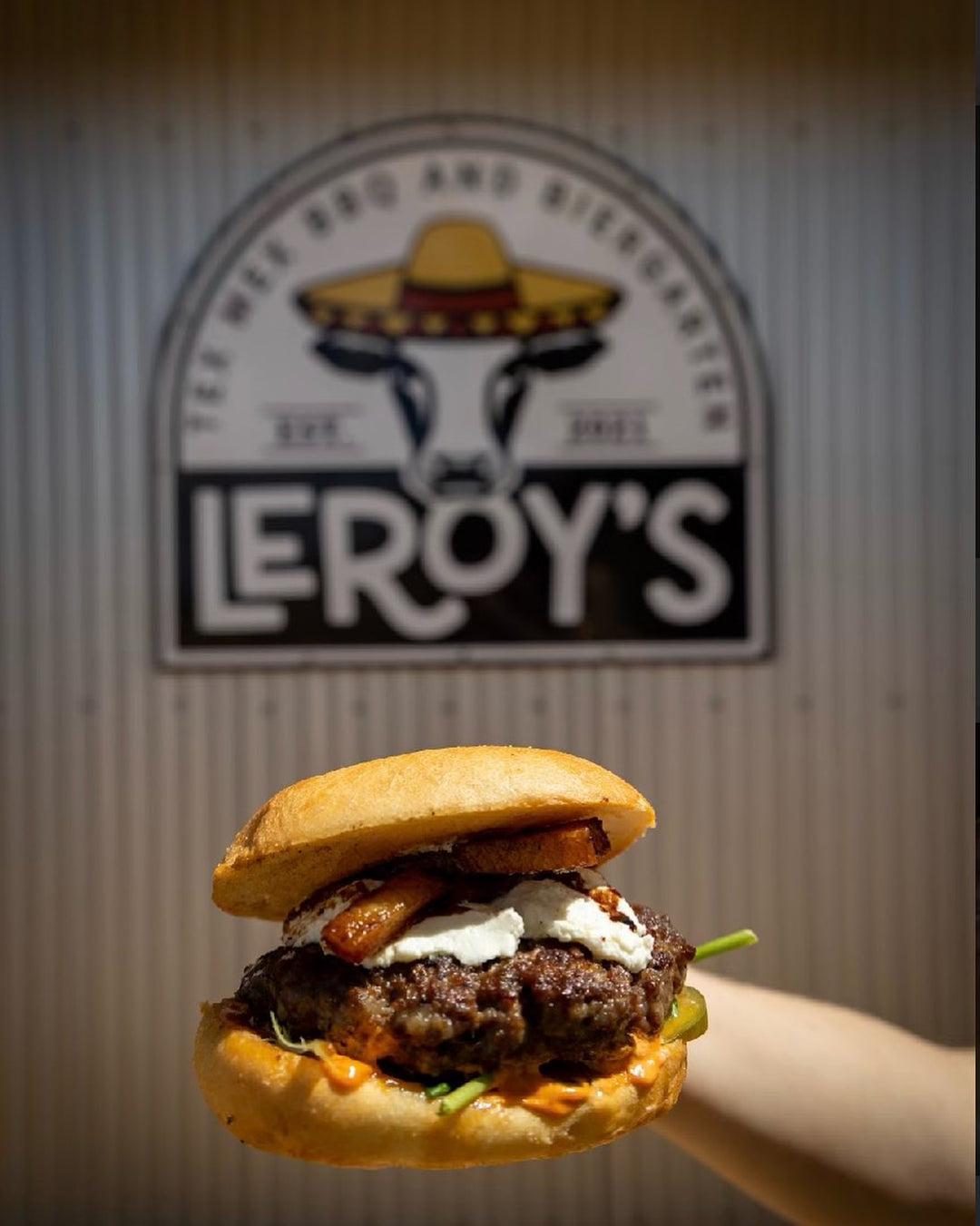 Leroy's specialty burger with toasted bun, beef patty, white cheese, and crispy bacon.