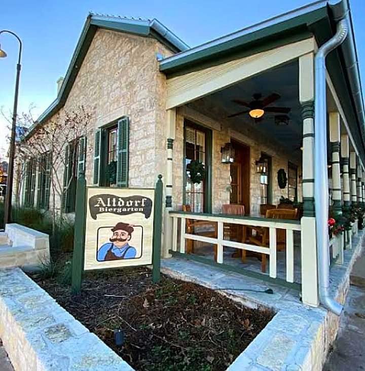 Altdorf Biergarten rustic stone exterior with green trim, outdoor patio, and wooden sign.