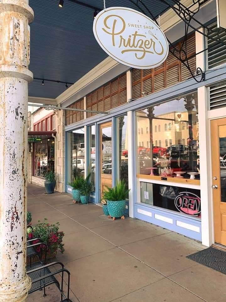 Pritzer Sweet Shop exterior with blue trim, large windows, wooden door, and teal planters