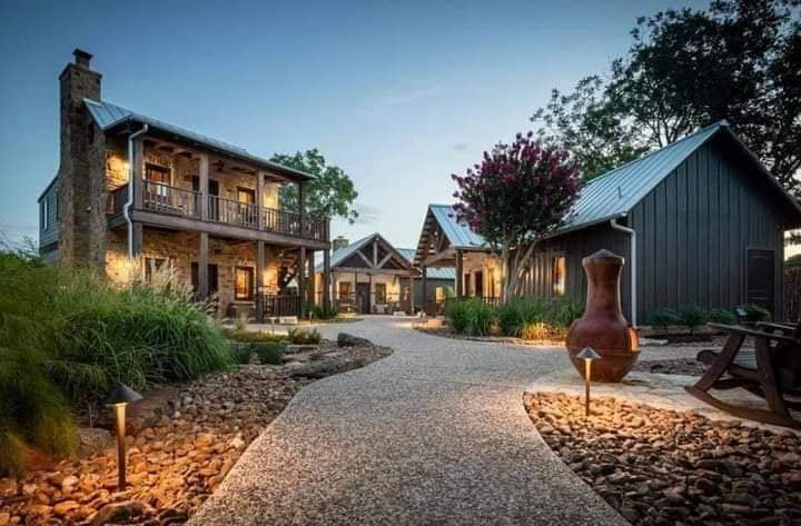 Rustic stone and wood guesthouse with metal roof, landscaped garden, and outdoor chiminea at dusk