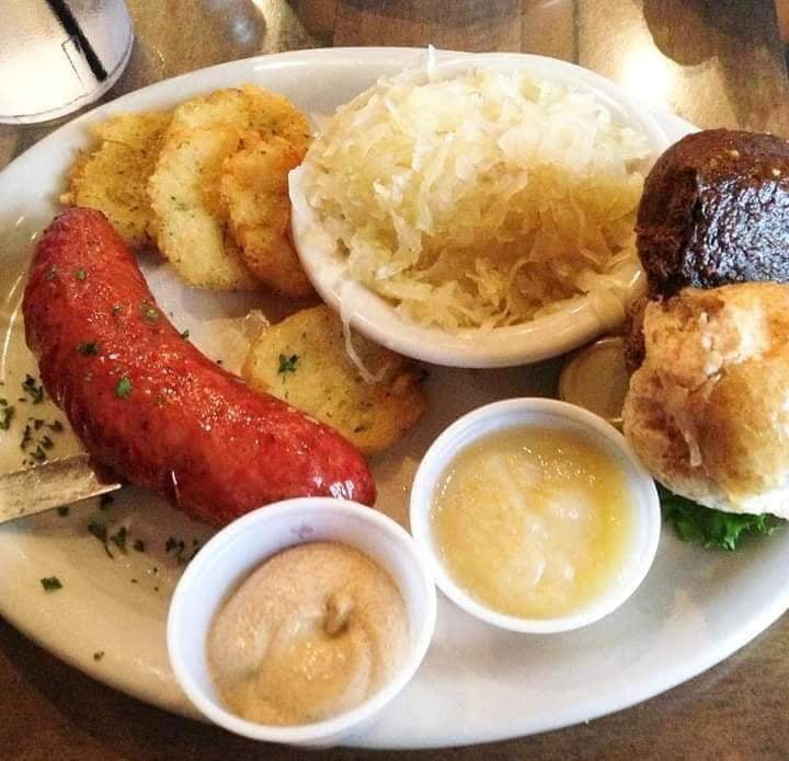 Smoked sausage with sauerkraut, potato pancakes, mustard, applesauce, and fresh bread