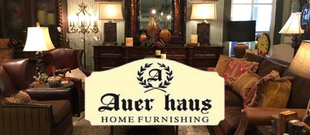 Auer Haus Home Furnishing living room set with brown leather sofas, wood tables, ornate lamps, and decorative accent pillows.