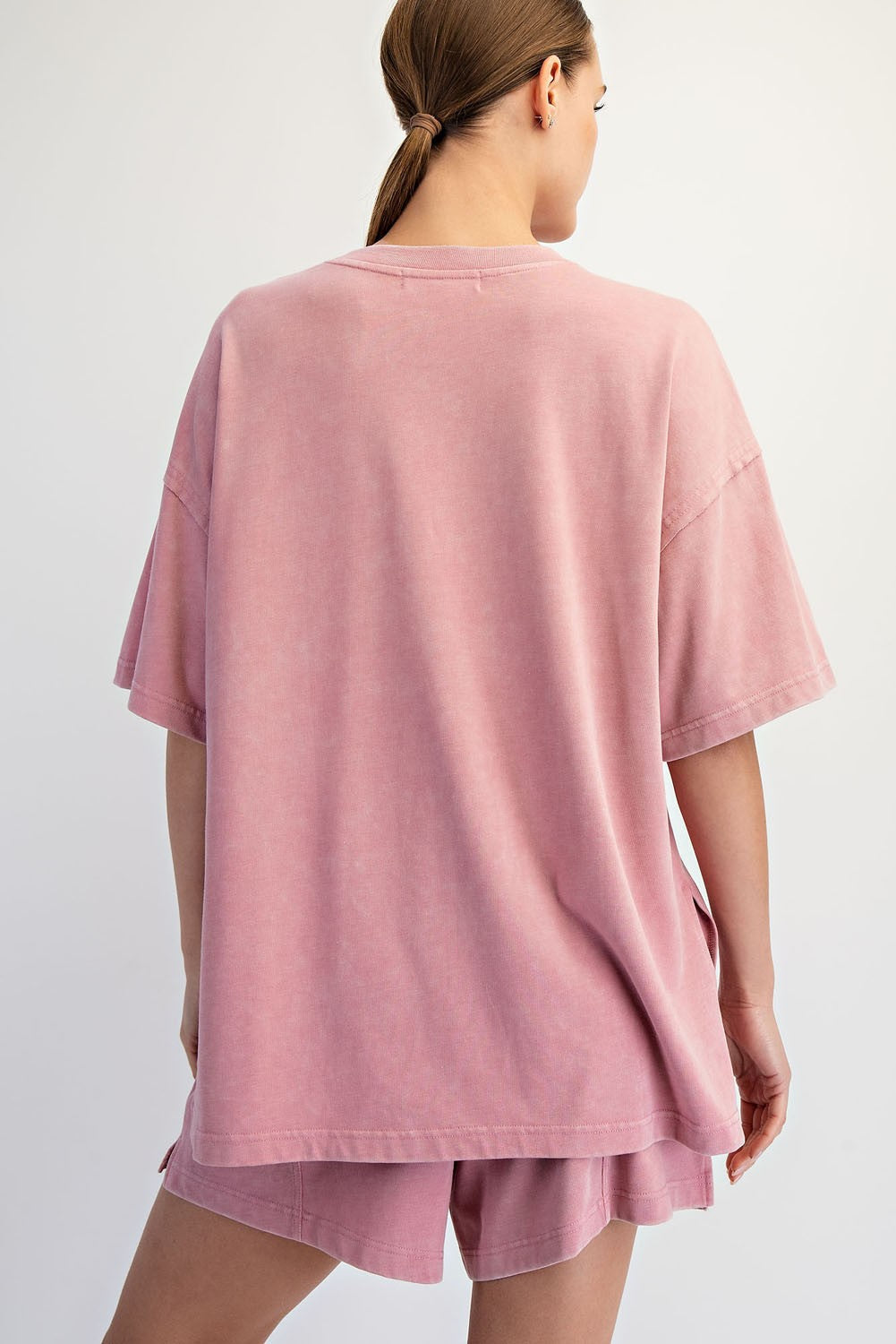 A woman with light brown hair in a low ponytail faces away from the camera, modeling Loca on Main&