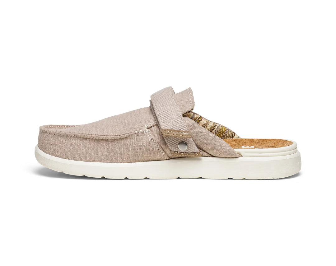 The Zertz M HAPPY HOUR LITE RESORT 1169850 is a beige, water-repellent slip-on mule featuring a canvas upper, cushioned white SugarLite outsoles, patterned fabric heel lining, and a stylish side strap with metal button accent.