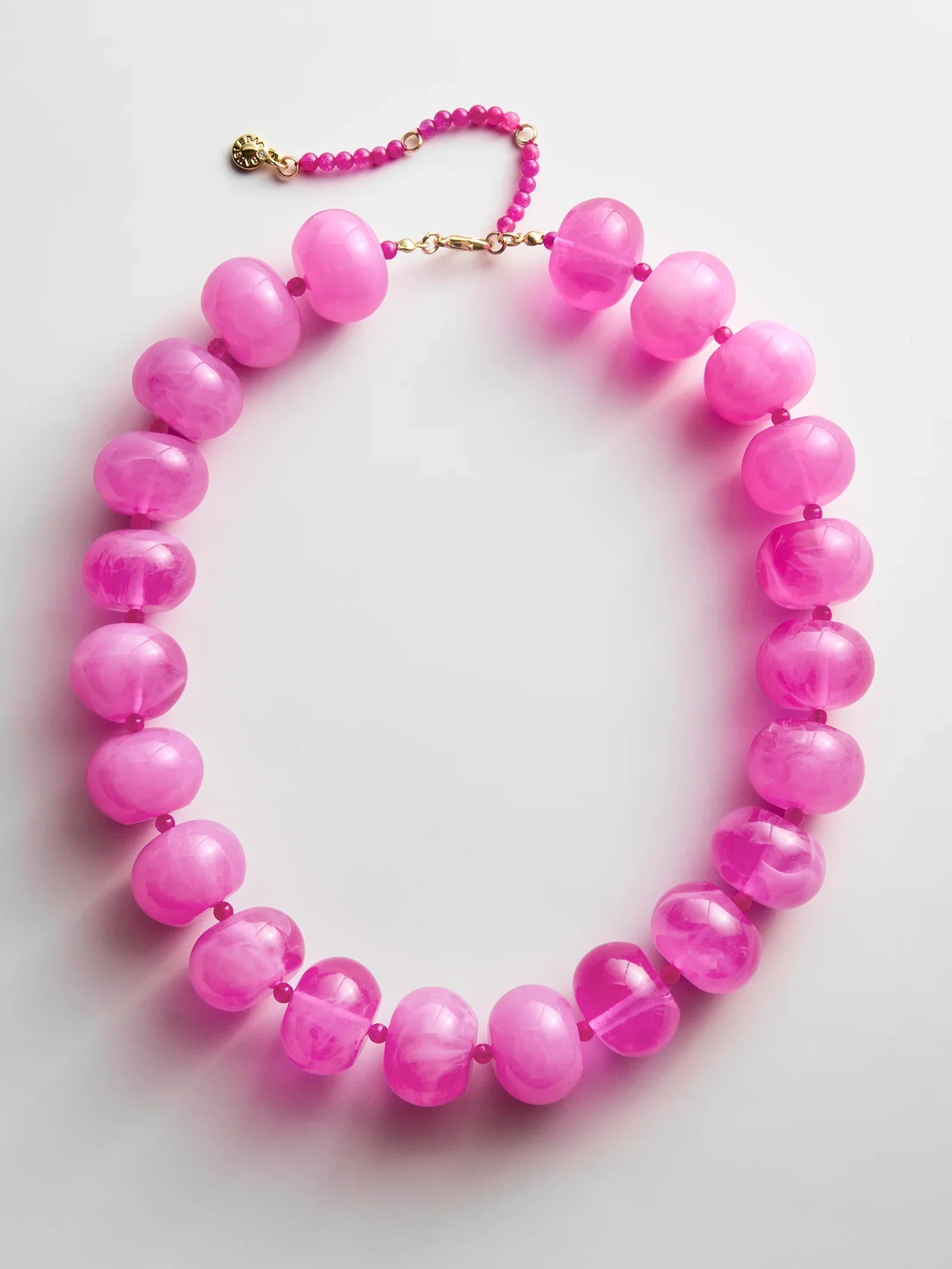 The JOAN SEMI PRECIOUS NECKLACE by Zertz features large, translucent round pink beads paired with smaller pink beads and finished with a gold clasp, displayed on a white background.