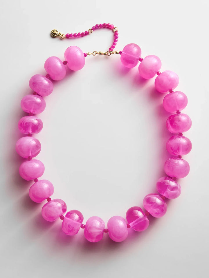 The JOAN SEMI PRECIOUS NECKLACE by Zertz features large, translucent round pink beads paired with smaller pink beads and finished with a gold clasp, displayed on a white background.