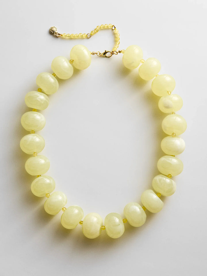 The JOAN SEMI PRECIOUS NECKLACE by Zertz features large, round, pale yellow beads on a gold chain with clasp, displayed against a white background.