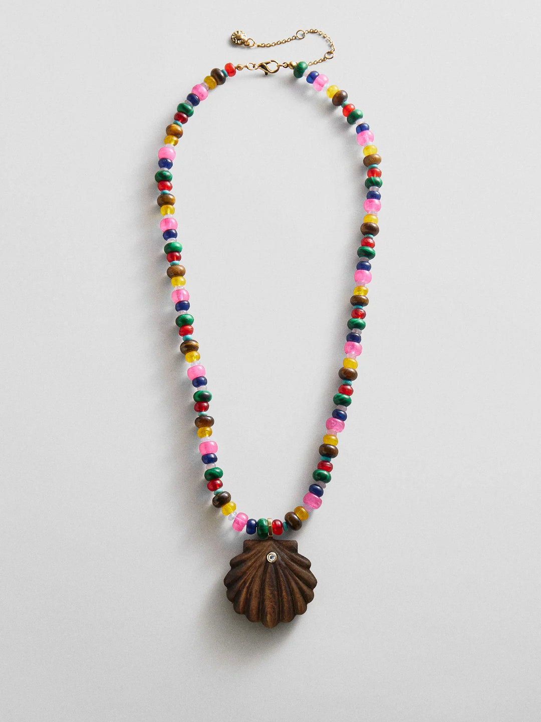 The Zertz SUN DRIFT SEMI-PRECIOUS PNDT NECK features multi-colored statement beads and a brown shell pendant with a rhinestone, adding ocean-inspired style to your look. Shown on a plain white background.