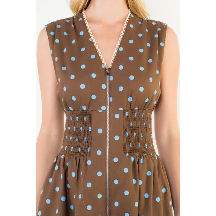 A close-up of the Zertz SLVLESS POLKA DOT MIDI DRESS in brown with light blue dots, featuring a V-neckline with white scalloped trim, a gathered elastic waist, and a front zipper.