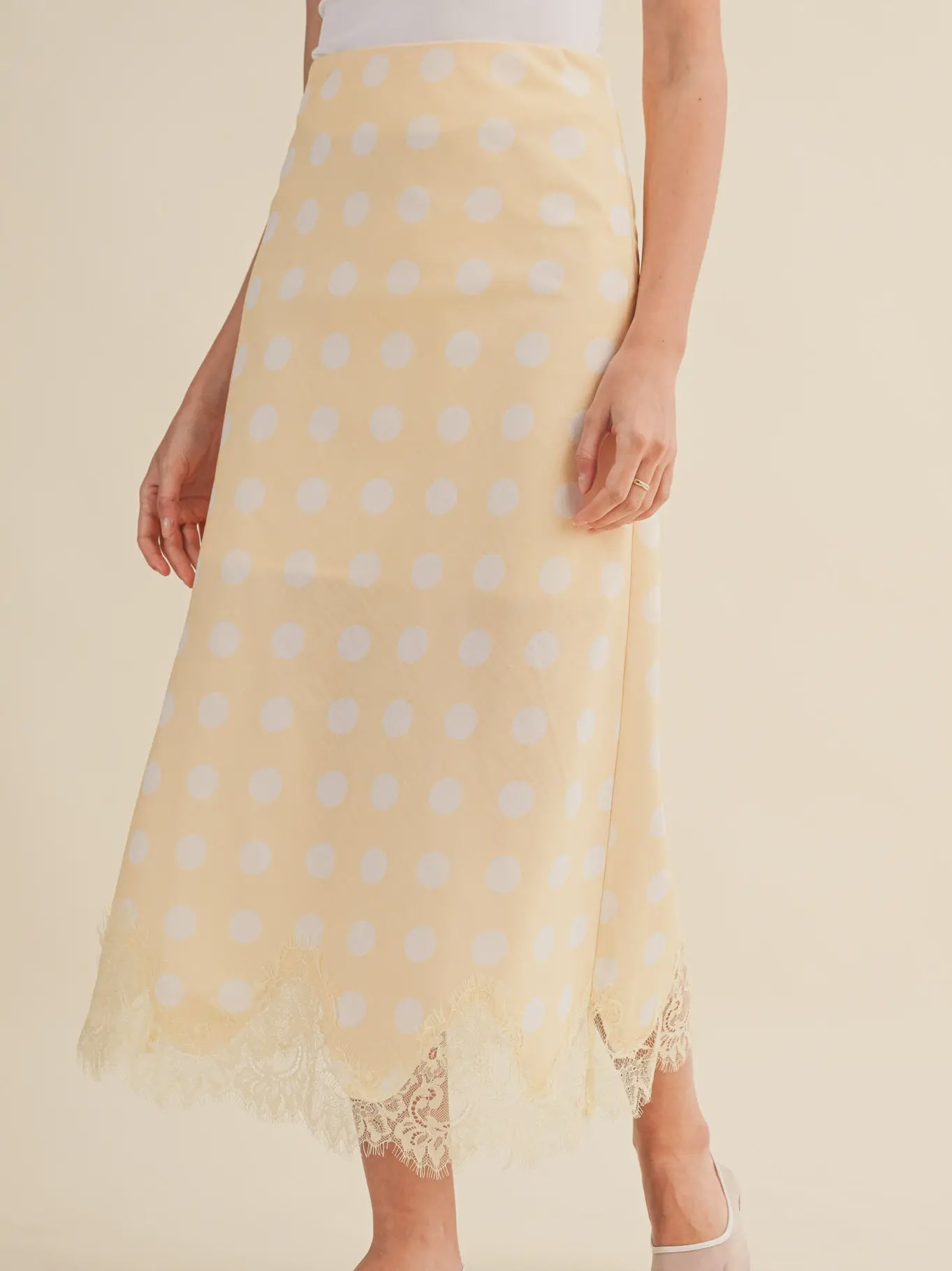 A person models the Zertz POLKA DOT LACE TRIM SKIRT, paired with a white top and matching shoes. Only the lower half of the body is shown.