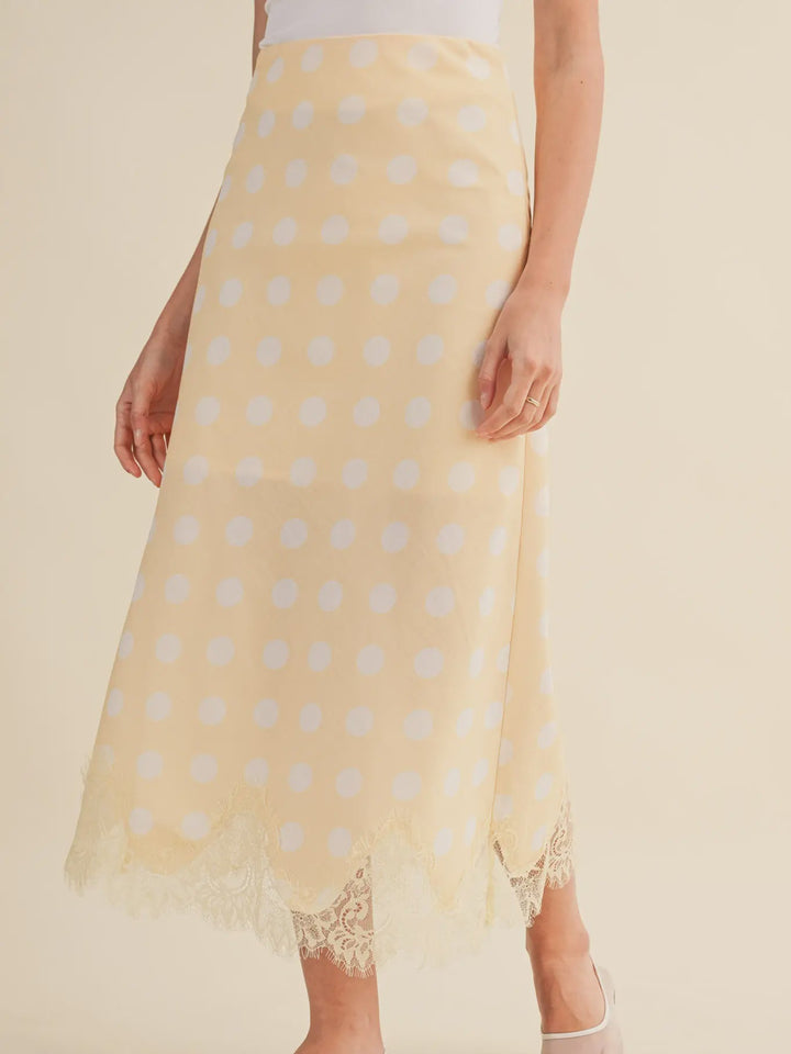 A person models the Zertz POLKA DOT LACE TRIM SKIRT, paired with a white top and matching shoes. Only the lower half of the body is shown.