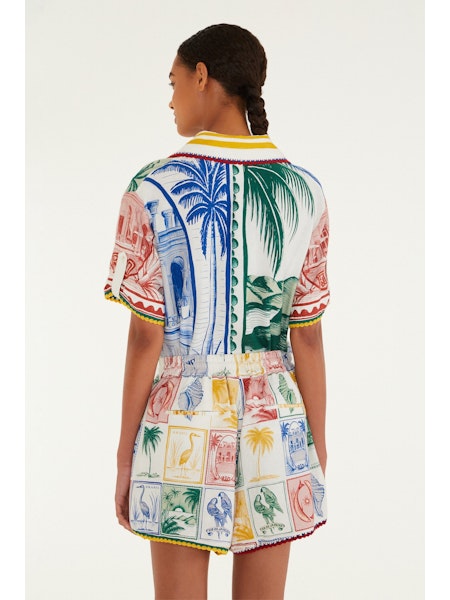 A woman with braided hair, seen from behind against a plain light background, wears a colorful matching shirt and Zertz BRASIL VINTAGE SHORTS featuring relaxed-fit tropical prints.