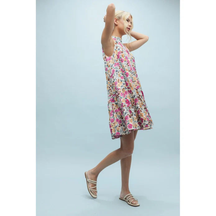 A woman with blonde hair tied back poses against a light blue background, wearing the Zertz SLVLESS PATTERN DRESS—a sleeveless, floral satin mini dress with an A-line silhouette and above-the-knee hem—paired with white slide sandals.
