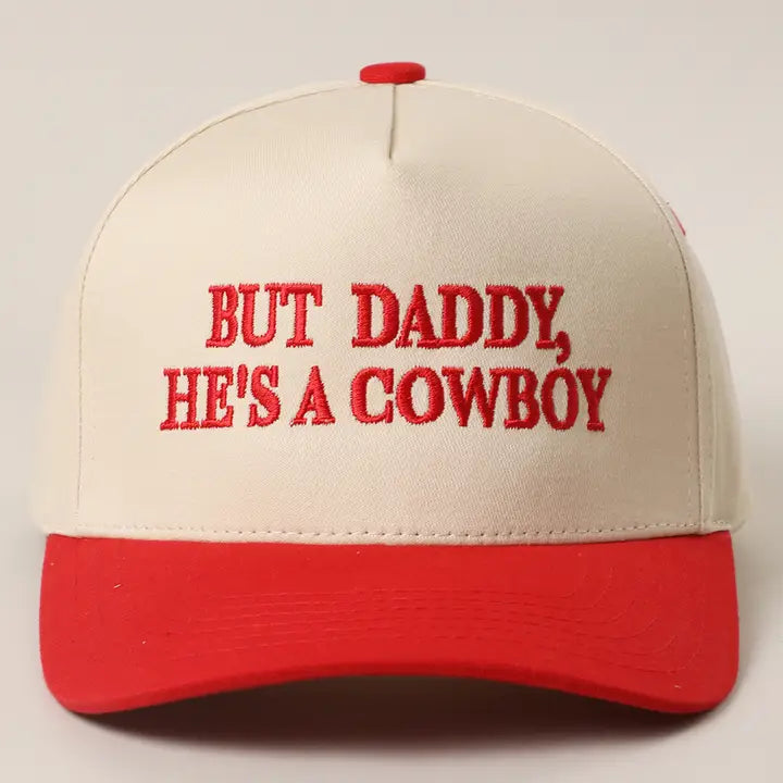 The He's A Cowboy Trucker Hat by Loca on Main is a beige and red two-tone hat with "BUT DADDY, HE'S A COWBOY" embroidered on the front. One size fits most for easy, stylish wear.