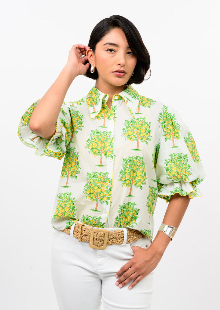 A woman poses against a white background in the Zertz LEMON TREE TOP paired with white pants, a woven beige belt, silver bracelet, and pearl earrings—effortlessly stylish as your go-to spring and summer top.