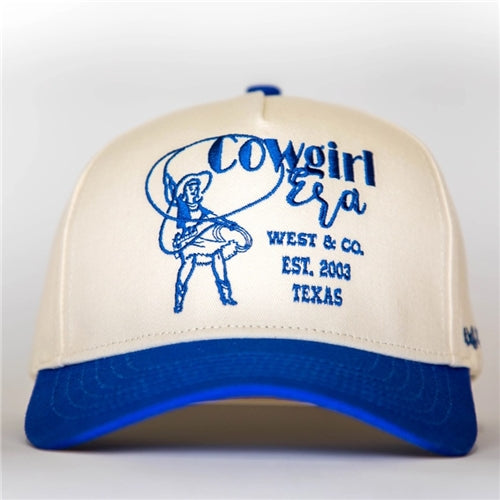 The Cowgirl Era Trucker Hat by Loca on Main is cream with a blue brim, featuring an embroidered cowgirl lasso design and "Cowgirl Era, West & Co., Est. 2003, Texas" in blue on the front.