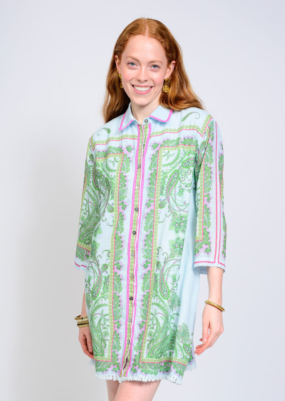 A woman with long red hair wears the Zertz PAISLEY SHIFT DRESS, a light blue shirt dress with green and pink paisley print, three-quarter sleeves, button-down front, and a relaxed fit. She stands against a plain white background.