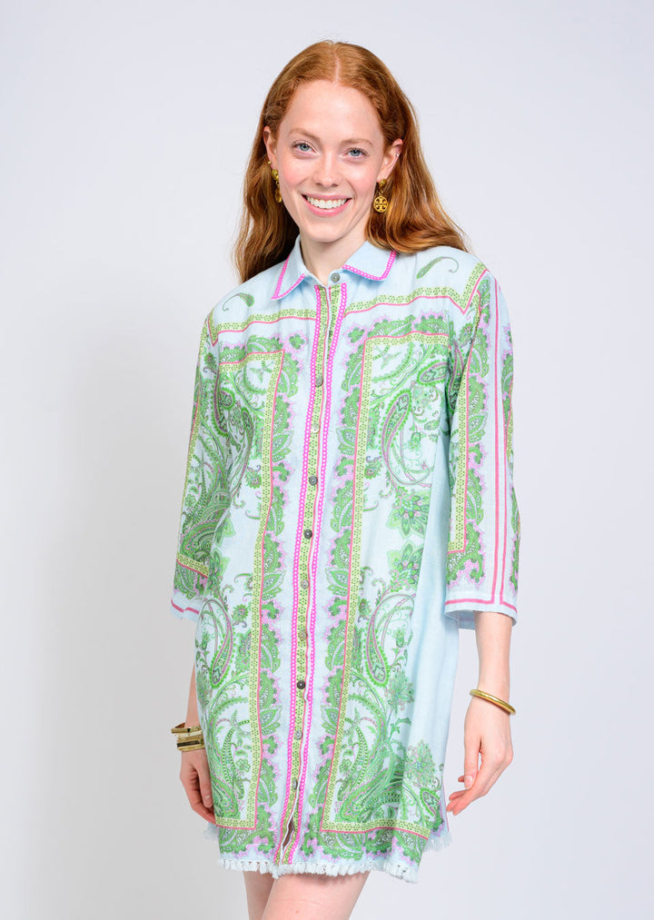 A woman with long red hair wears the Zertz PAISLEY SHIFT DRESS, a light blue shirt dress with green and pink paisley print, three-quarter sleeves, button-down front, and a relaxed fit. She stands against a plain white background.
