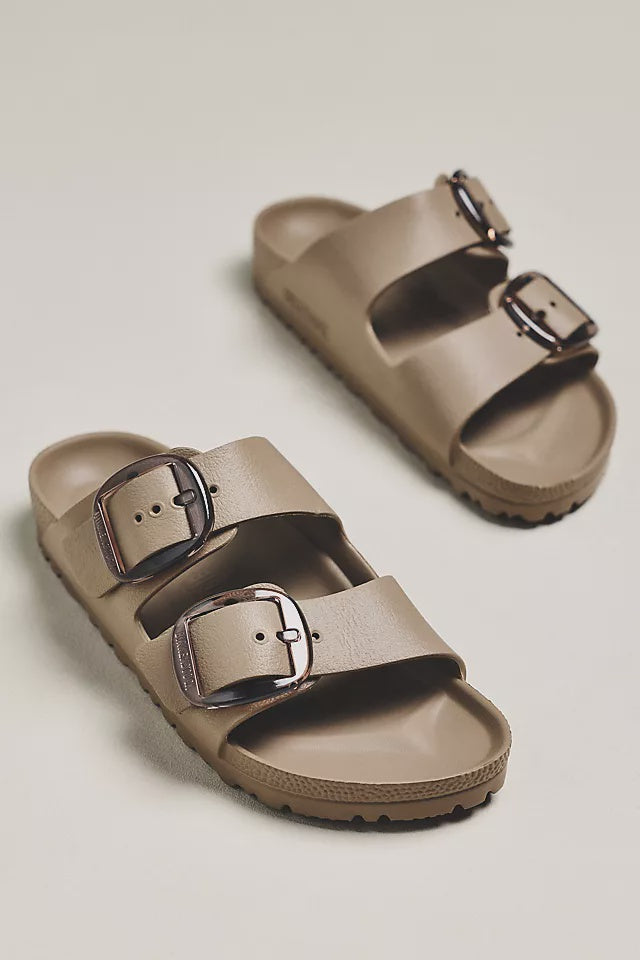 A pair of Zertz ARIZONA BIG BUCKLE EVA GRAY TAUPE N sandals with two wide straps and large metal buckles, displayed on a light beige surface. Lightweight, slip-on, and water-resistant for comfort and modern style.
