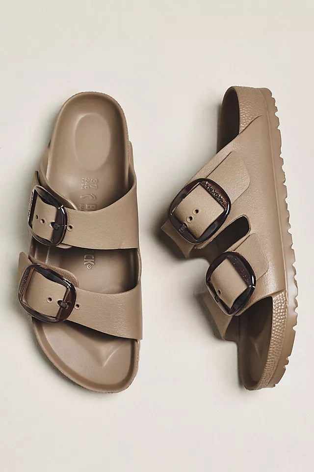 A pair of Zertz ARIZONA BIG BUCKLE EVA GRAY TAUPE N lightweight slip-on sandals with two wide straps and large brown buckles, shown on a light background—one sandal facing up, the other on its side.