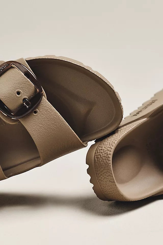 Close-up of Zertz ARIZONA BIG BUCKLE EVA GRAY TAUPE sandals featuring a lightweight, water-resistant design with textured footbeds, treaded soles, and a large metallic buckle on one slip-on.