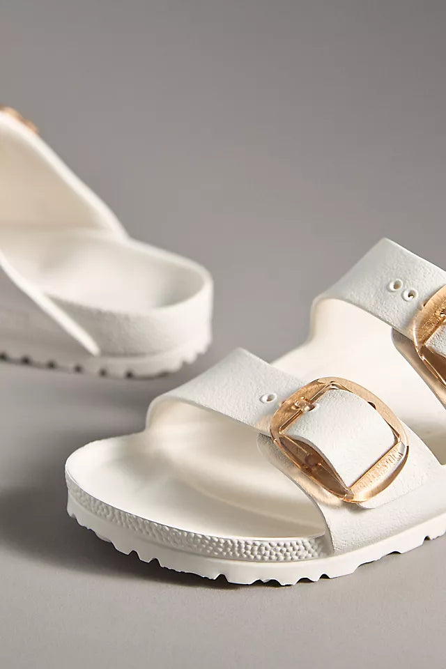 The Zertz ARIZONA BB EVA EGGSHELL N sandals feature two wide straps with large gold buckles, a textured sole, and an ultra-lightweight design. One sandal is in sharp focus in the foreground; the other appears slightly blurred behind.