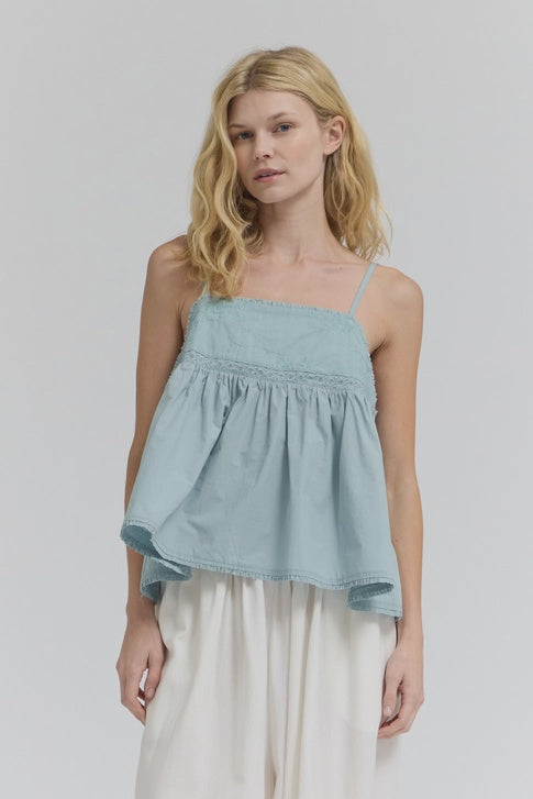 A woman with wavy blonde hair models the Zertz EMBROIDERED SLEEVELESS TOP, pairing it with white wide-leg pants for a chic, casual look against a plain light gray background.