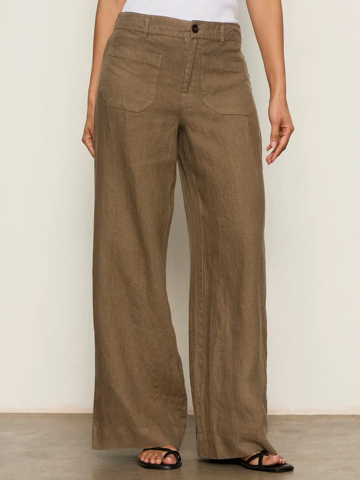 Someone stands against a neutral background wearing Zertz THE LINEN MARINE WIDE LEG PANT CP1043716 in brown, featuring front patch pockets, styled with black sandals and a white top.