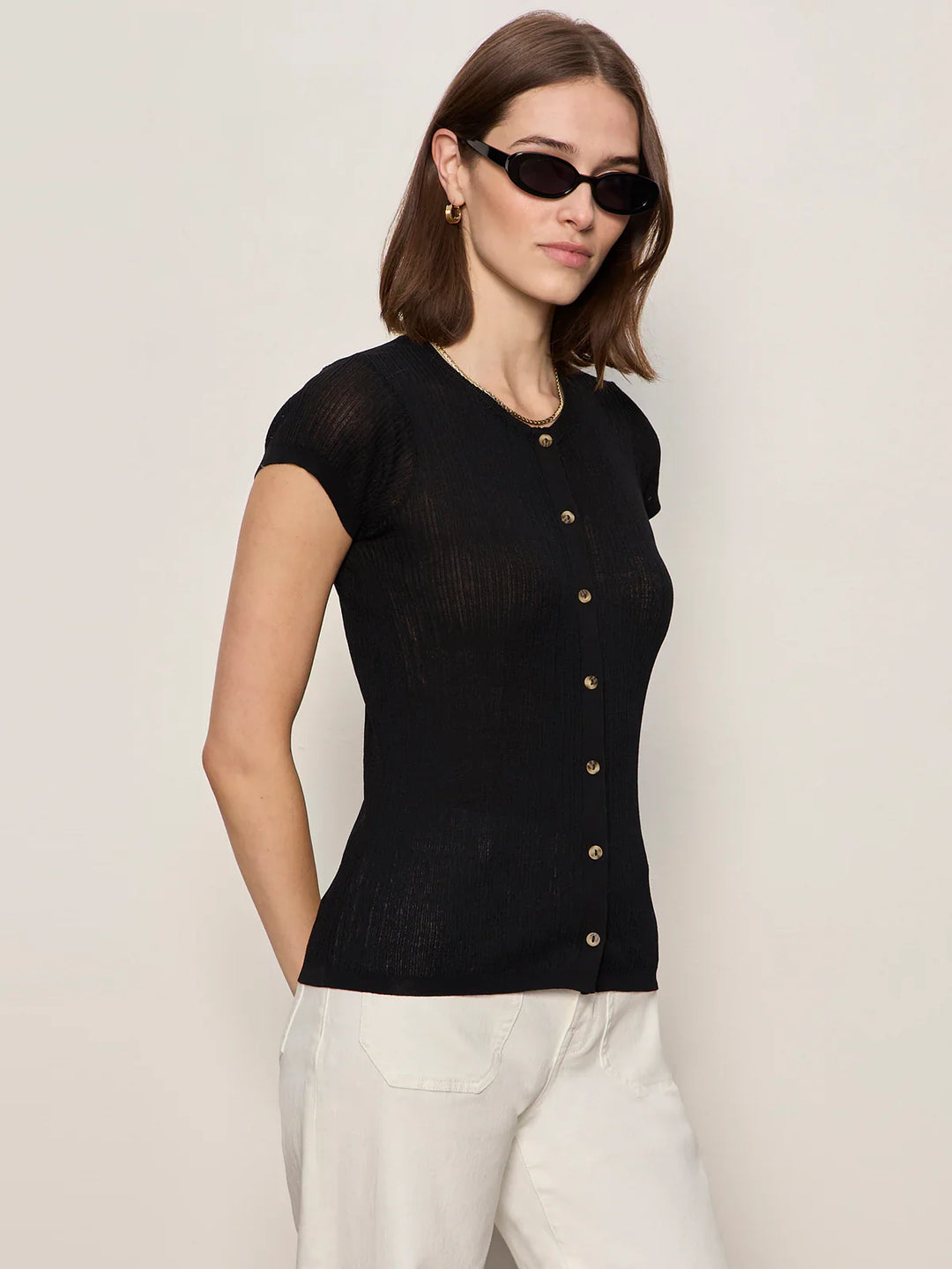 A woman stands against a plain light background with her hands behind her back, wearing Zertz&