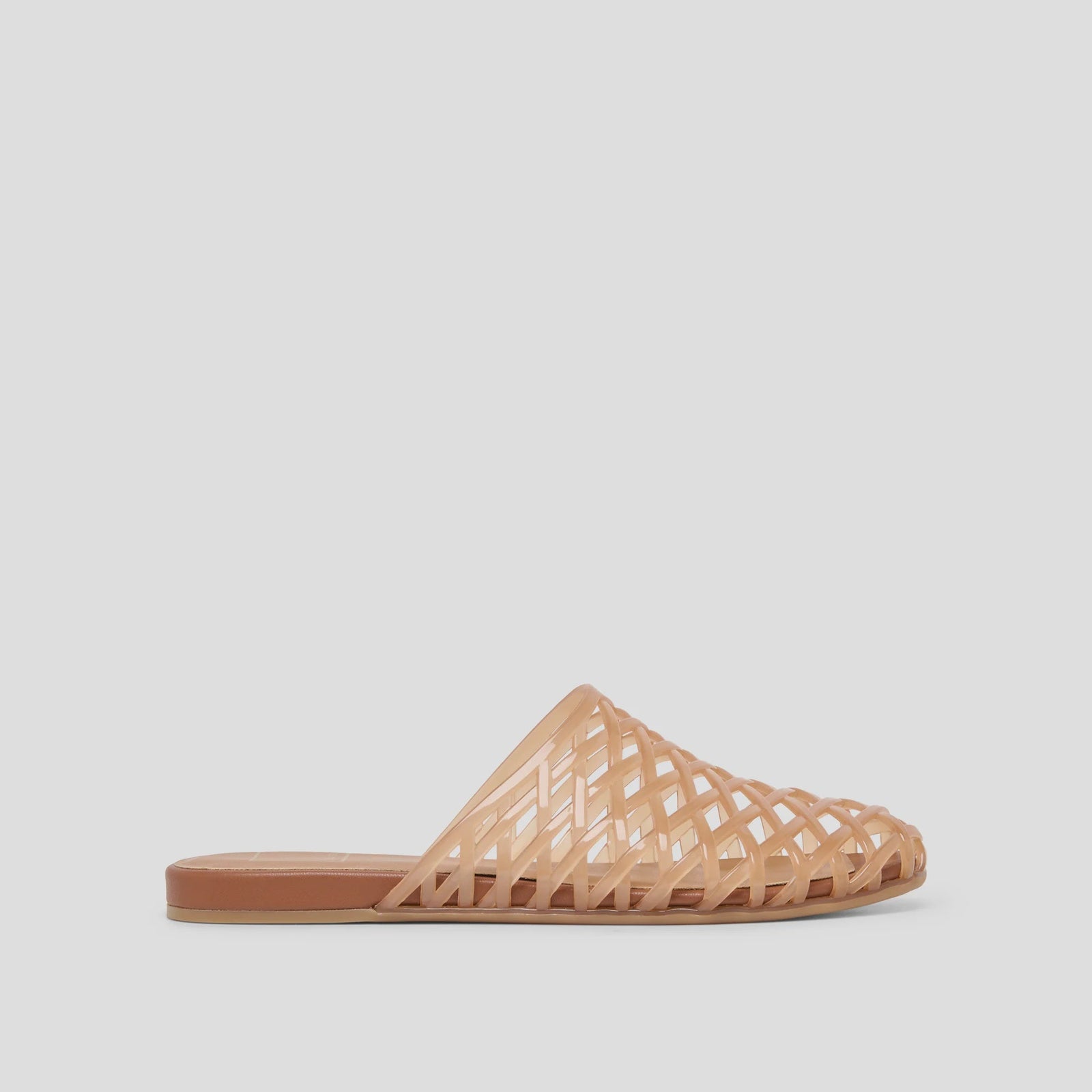 The Zertz GINNA JELLY FLATS are tan slip-on sandals featuring a flat sole and woven lattice design, made from a water-based leather alternative, shown in a side view against a plain light gray background.
