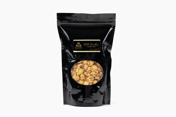 A black resealable bag of Hill Country Chocolate’s Hill Country Caramel Popcorn, caramel-coated and adorned with a gold and black label.