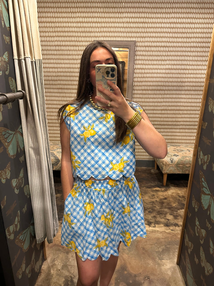 A woman stands in a fitting room taking a mirror selfie, wearing the Zertz 2 PIECE LEMON SET. Her playful look complements the butterfly wallpaper and patterned walls.