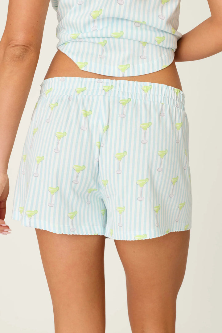 A person shown from the back wears Zertz PLAYFUL PRINTS SALTY CADILLAC PJ SHORTS in light blue and white striped cotton-modal jersey with a margarita glass pattern; their matching pajama top is partially visible.
