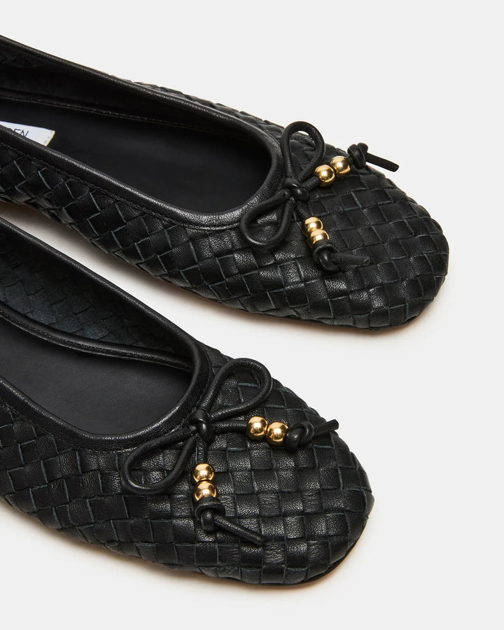 Close-up of Zertz DIVY LEATHER FLAT: black woven ballet flats featuring black bows and gold bead accents on the toe, elegantly displayed against a plain white background.