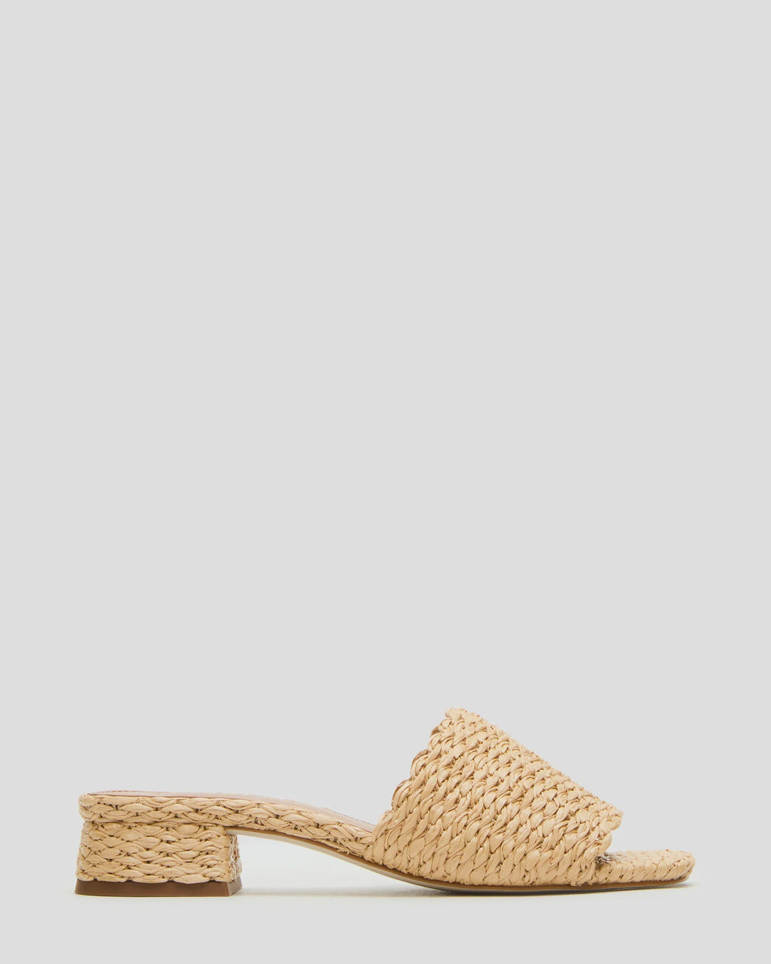 The MONTGOMERY SLIDE SANDAL by Zertz features a wide braided raffia strap, scalloped edges, a low block heel in natural beige, and a chic square-toe profile, shown against a light grey background.