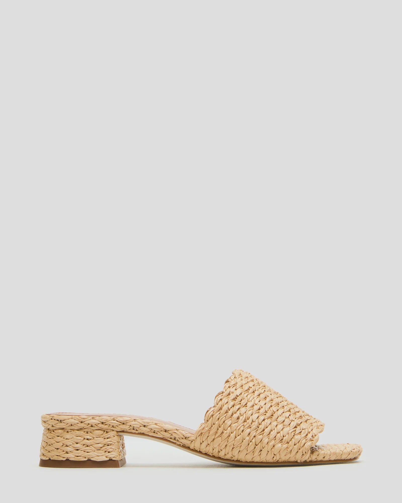 The MONTGOMERY SLIDE SANDAL by Zertz features a wide braided raffia strap, scalloped edges, a low block heel in natural beige, and a chic square-toe profile, shown against a light grey background.