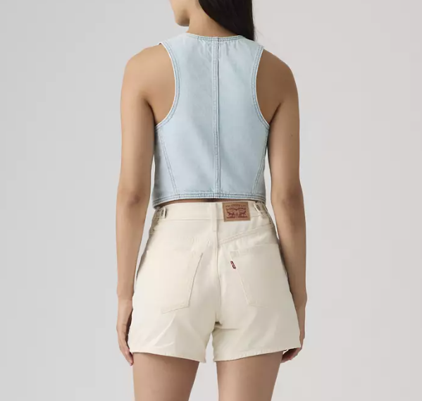 A woman is seen from the back wearing a light blue Zertz RACER VEST - NEVER GOING TO CHANGE as a crop top with high-waisted, light beige shorts featuring a visible Levi’s leather patch above the right pocket.