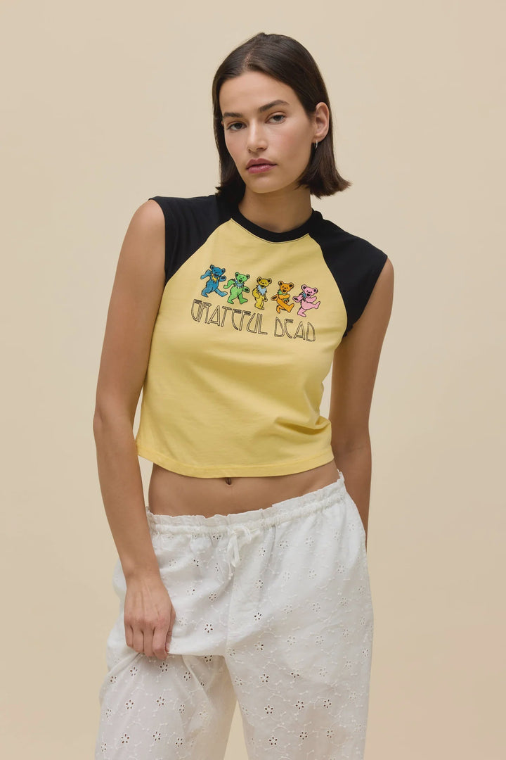 A woman with short brown hair wears the Zertz GREATFUL DEAD BEARS RGLAN TEE with dancing bears, paired with white eyelet pants, standing against a plain beige background.