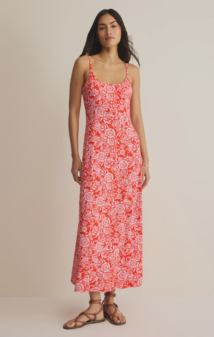 A woman stands against a plain background wearing the Zertz CHARISMA ONA FLORAL MIDI DRESS, a sleeveless, ankle-length floral dress with adjustable spaghetti straps, paired with brown flat sandals.
