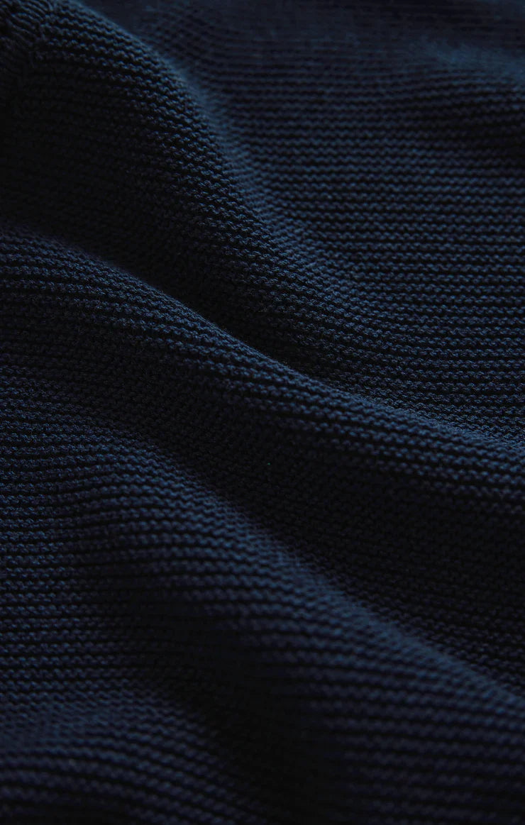 Close-up of the SANDBAR CROCHET MINI DRESS by Zertz, featuring dark navy blue knitted fabric with textured stitches and gentle folds—ideal as a beach cover-up or stylish mini dress.