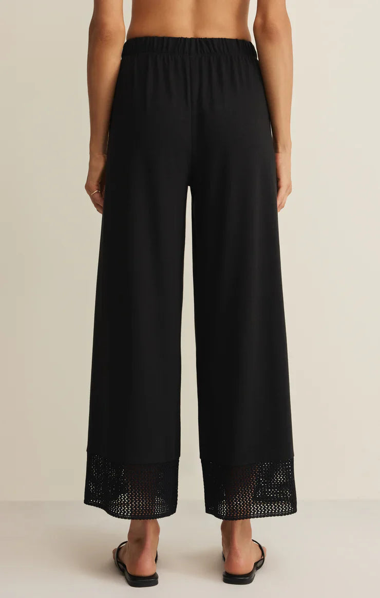 A person, barefoot and seen from the back against a plain light background, wears the Zertz BANYAN PANT—relaxed straight-leg pants featuring an elastic waistband and mesh hem detail.