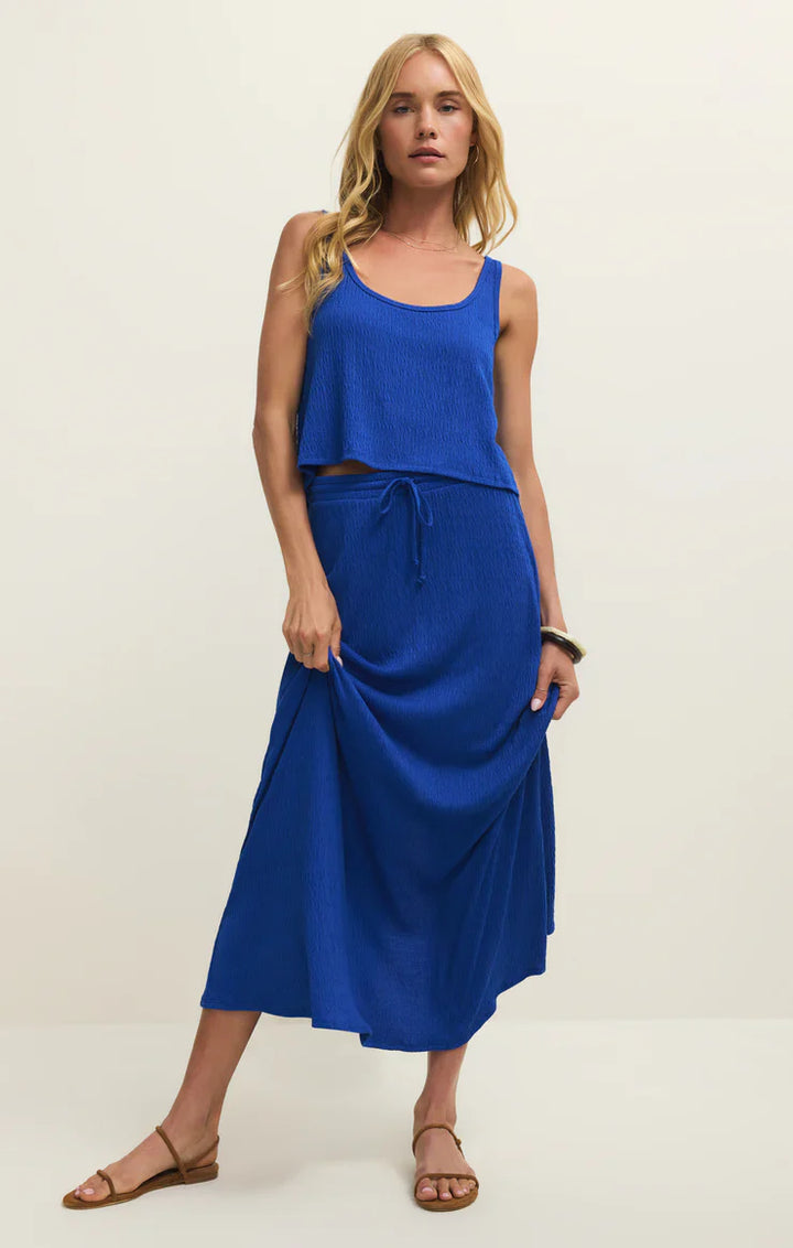 A woman with long blonde hair wears the Zertz JOANNA TANK in royal blue, paired with a matching drawstring midi skirt and sandals, standing against a plain light background.