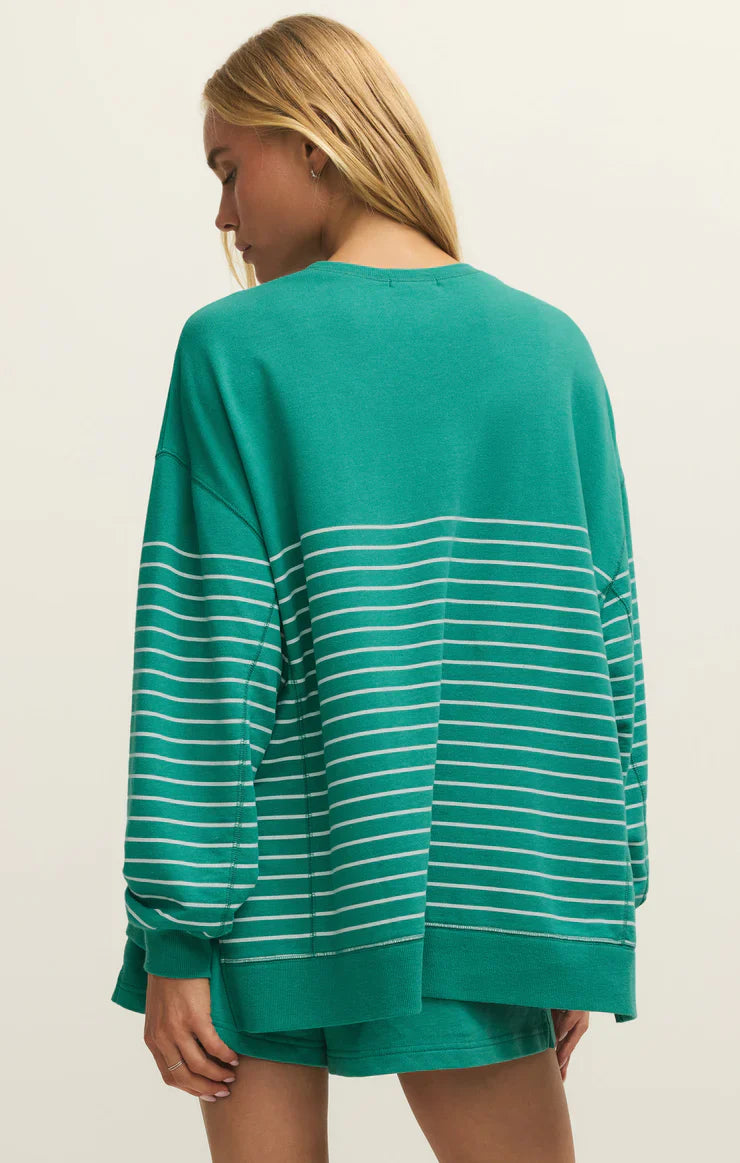 A woman with long blonde hair is seen from the back wearing the Zertz MODERN WEEKENDER STRIPE LA PALMA baby french terry crewneck in green with white stripes, paired with matching shorts for a comfy, casual look.