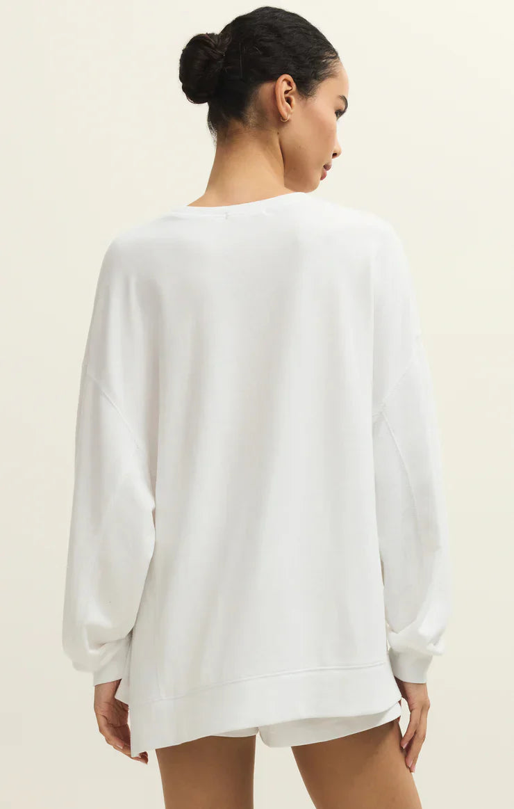 A woman with dark hair in a bun is seen from the back, wearing the Zertz MODERN WEEKENDER WHITE baby french terry crewneck sweatshirt and white shorts against a plain light background—your perfect weekend look.
