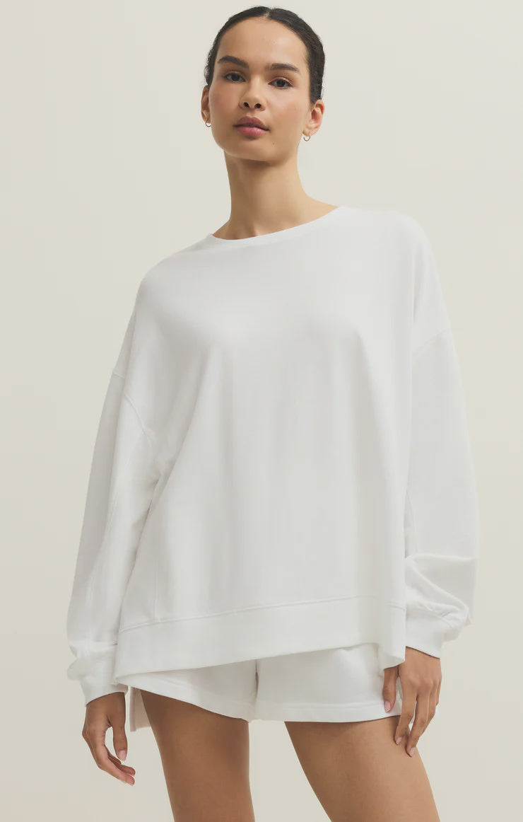 A person stands against a plain light background, wearing the Zertz MODERN WEEKENDER WHITE oversized baby french terry crewneck sweatshirt with matching white shorts—the perfect weekend uniform. Their hair is pulled back as they look confidently at the camera.