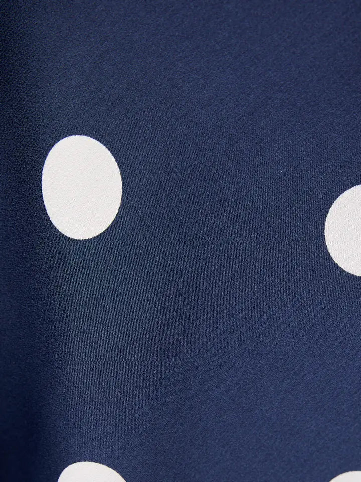 A close-up of navy blue fabric with large white polka dots, ideal for the MINI SATIN SKIRT by Zertz.