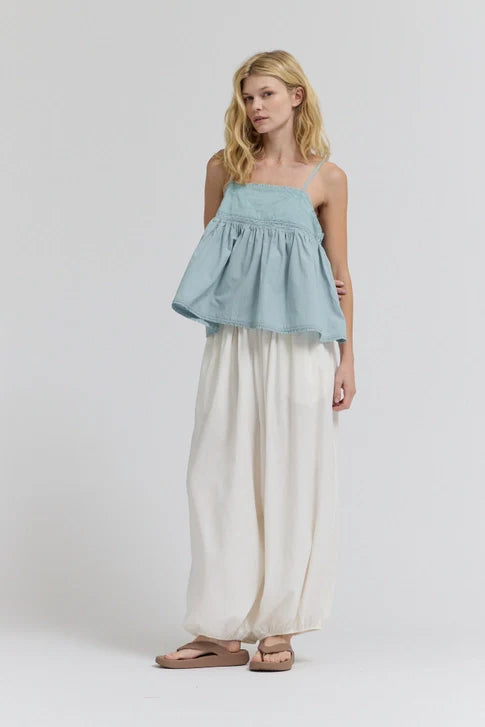 A woman with blonde hair stands against a plain background, wearing Zertz&