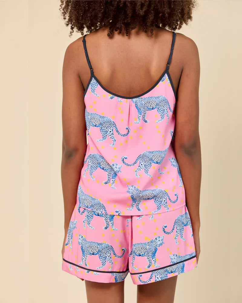 A person with curly hair wears the Zertz COSMIC CHEETAH CAMI SHORTS SET, a pink adjustable cami top and matching shorts with blue cheetahs and yellow stars, shown from the back against a plain beige background.