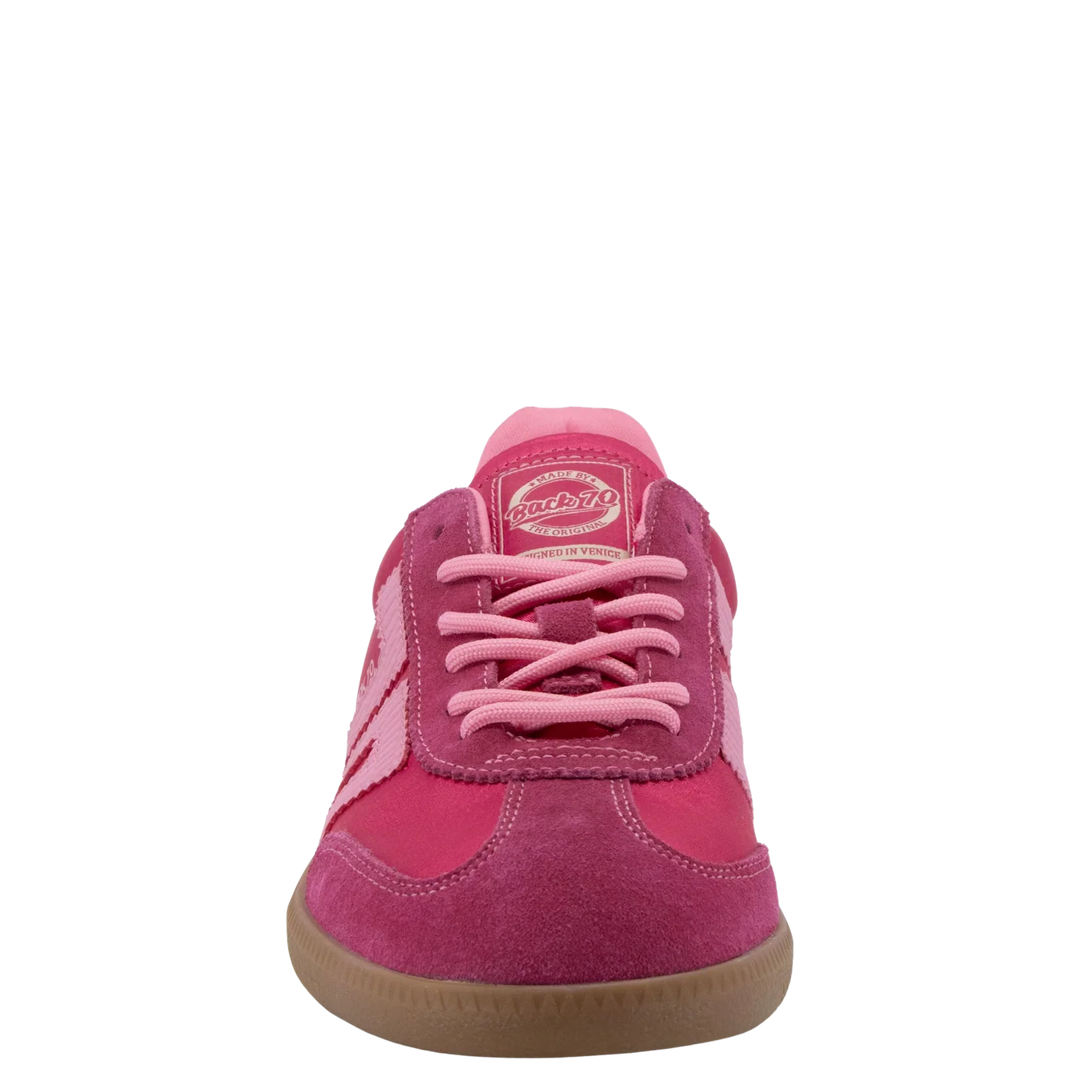 A front view of the Zertz GHOST C26 IN FUXIA SNEAKER showcases its pink and magenta suede, light pink laces, gum rubber sole, and logo patch on the tongue, embodying a bold sporty look against a plain white background.