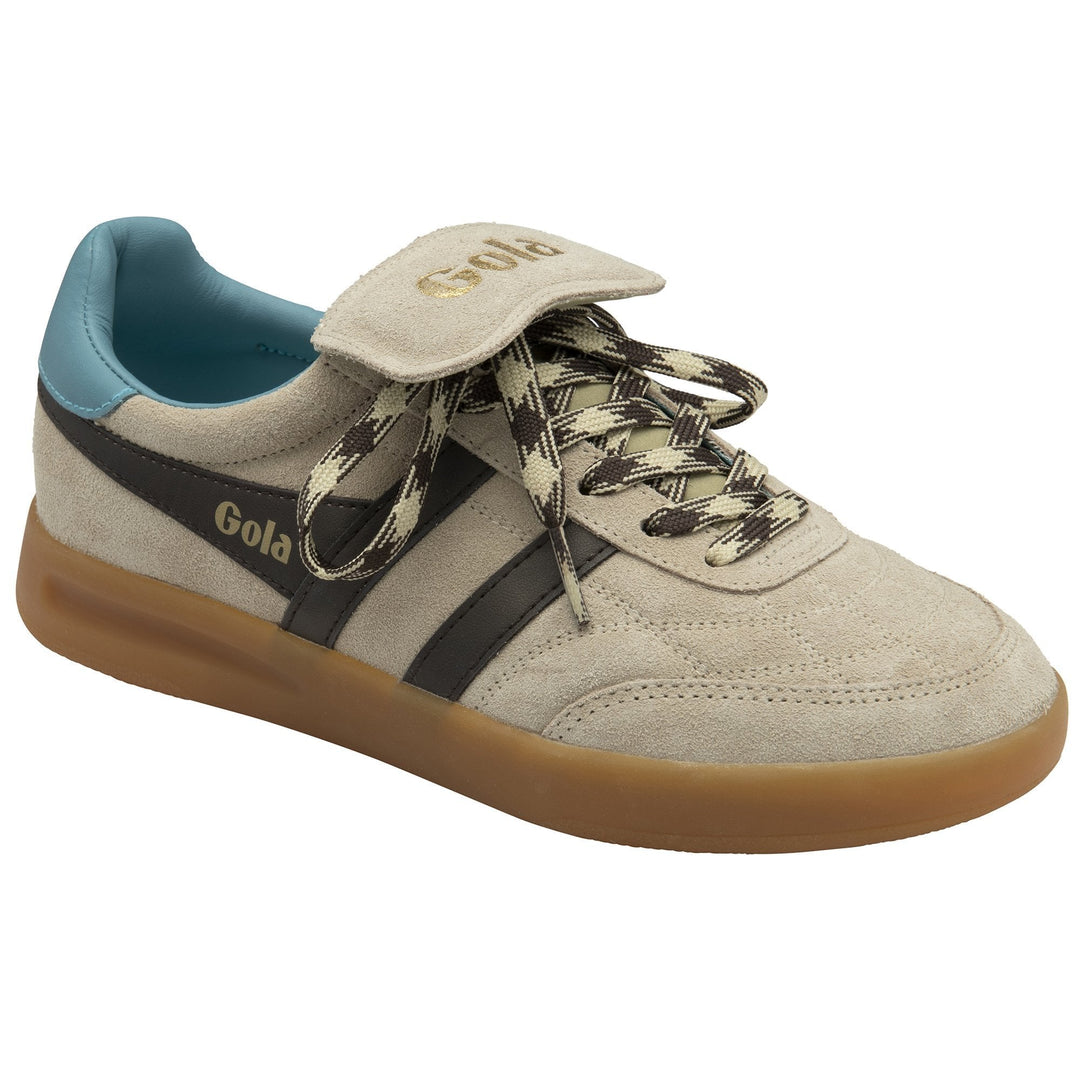 The Zertz STADIA 86 TRAINER BONE/MOCHA/OCEAN/GUM is a women’s sneaker in beige suede, inspired by vintage football styles, featuring a gum sole, blue lining, black stripes, chevron laces, Velcro strap, and gold logo.
